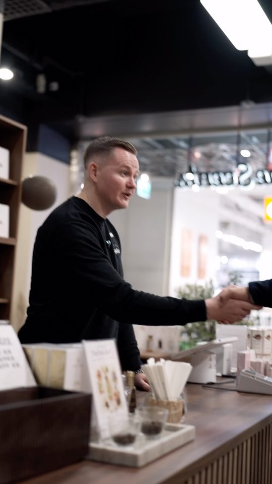 Stillbild ur reel: medarbetare skakar hand med en kund över disken.